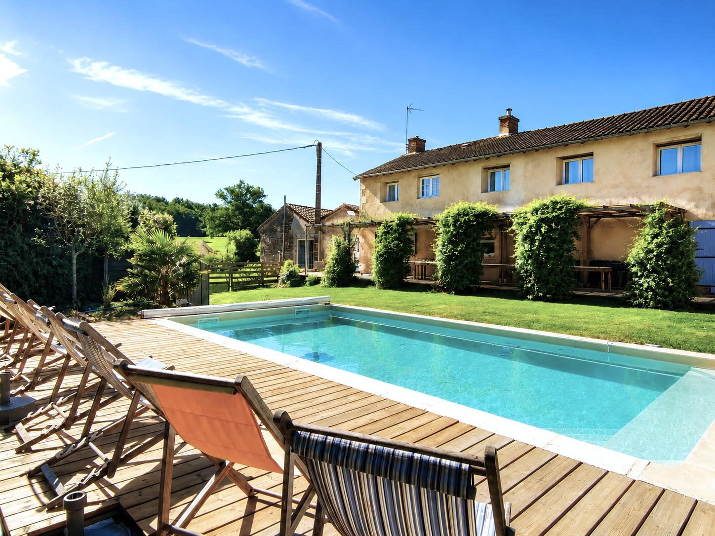 Piscine extérieure du domaine entourée d'une terrasse et de végétation